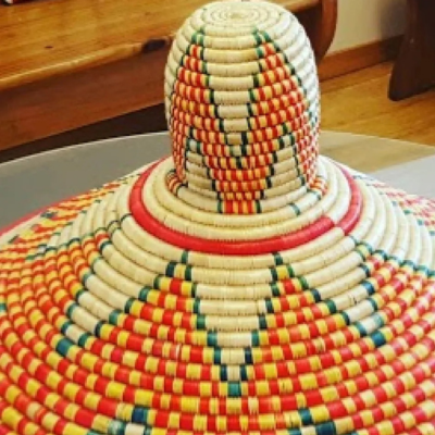 Traditional Ethiopian woven mesob basket with vibrant red, yellow, and green patterns, used for communal dining.